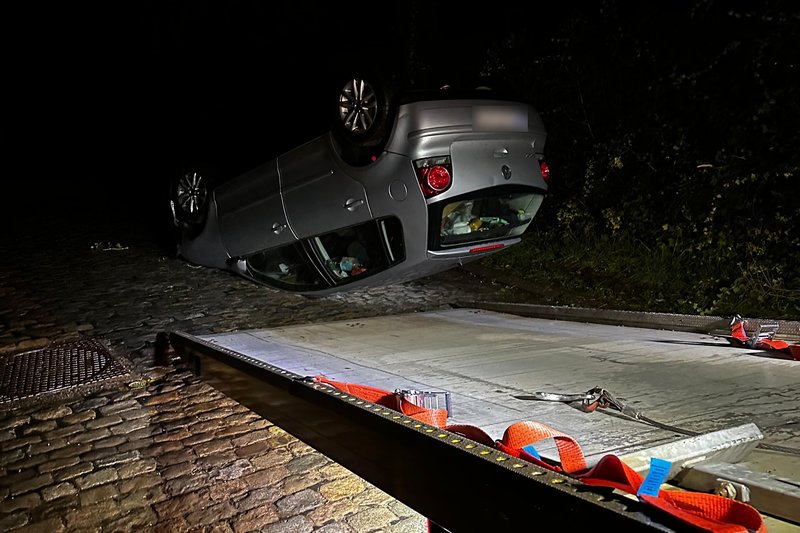 Polo retournée dans une rue pavée de La Hulpe, la nuit, avant son chargement sur la dépanneuse HELPCAR